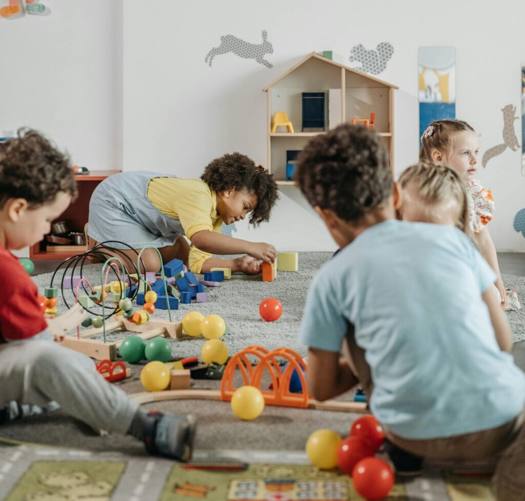 A lively group of children playing inside a colorful kindergarten classroom.